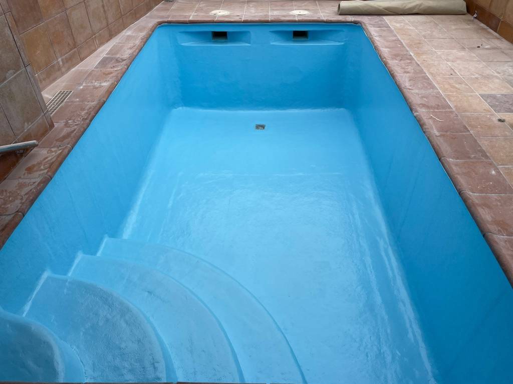 Piscina revestida en poliéster azul con escalera de obra, terminada