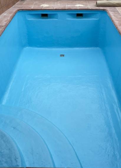 Piscina revestida en poliéster azul con escalera de obra, terminada