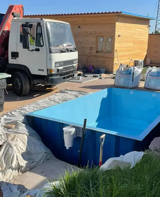 Camión grúa colocando una piscina de poliéster en el hueco ya excavado